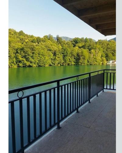 a black fence next to a lake with trees at H&E Vikendica na vodi, Jezero Perucac 