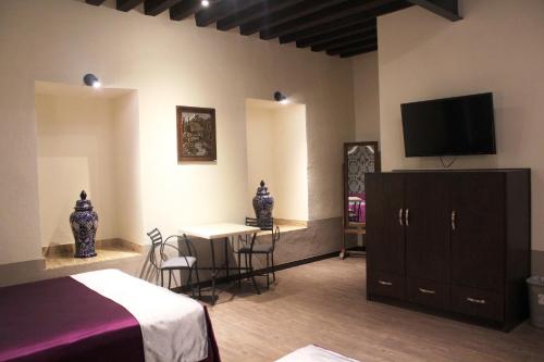 a bedroom with a bed and a table and a tv at Hotel Gala in Puebla