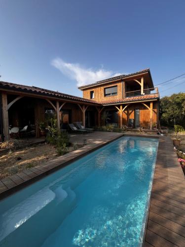 VillevieilleにあるVilla en boisの家の前にプールがある家