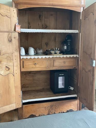 une armoire en bois avec une cuisine équipée d'un micro-ondes dans l'établissement Maison Côté Halle La chambre de l'Artiste, à Saint-Flour