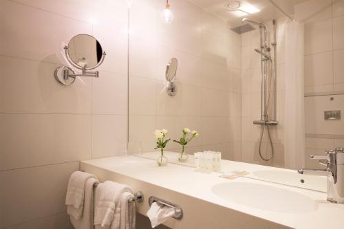 a white bathroom with a sink and a mirror at Grand Hotel Alingsås in Alingsås