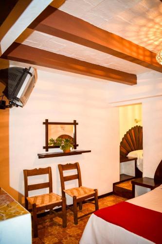 a living room with two chairs and a bed at Hotel Posada Santa Anita in Taxco de Alarcón
