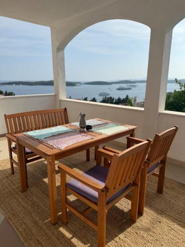 a wooden table and chairs on a porch with a view of the ocean at Apartments Biba Hvar in Hvar