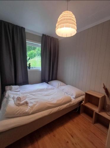 a bed in a room with a window and a chandelier at Nesvika nature reserve Apartment only 20 min away from Bergen in Bergen