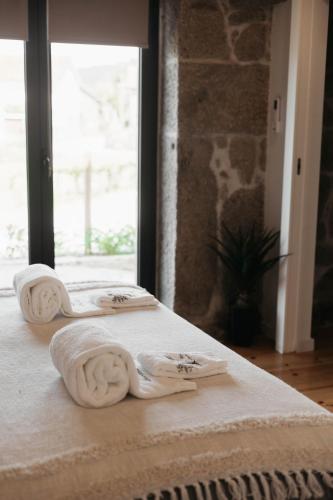 two beds with towels on them in a room with a window at Casa Laurinha by Lethes Legacy in Ponte de Lima
