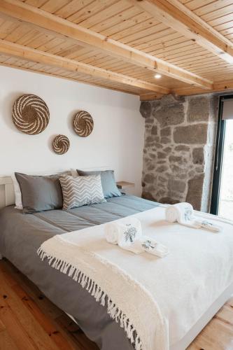 a large bed in a room with a stone wall at Casa Laurinha by Lethes Legacy in Ponte de Lima