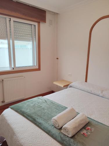 a bedroom with two towels on a bed with a window at Pensión Armonía in Caldas de Reis