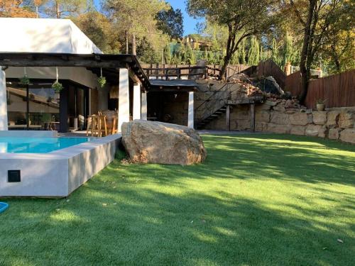 une cour avec un grand rocher et une piscine dans l'établissement Oasis en el Montseny con piscina, jardín y natura, à Seva