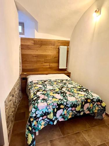 a bed with a floral comforter in a bedroom at BnB Tana del Gufo in Abbadia Lariana