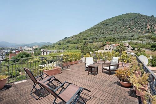 a patio with chairs and tables and a mountain at Hepburn Holiday Home in Salerno