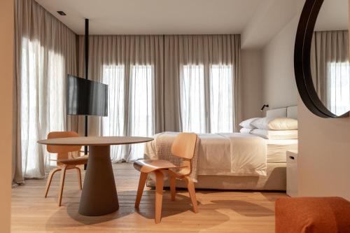 una camera da letto con un letto, un tavolo e delle sedie di Alma Suites a Lido di Jesolo