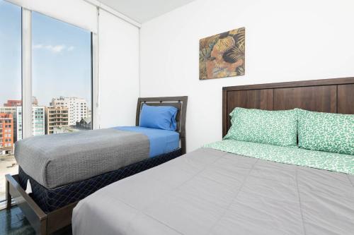 a bedroom with two beds and a large window at Gorgeous 3BR High-Rise with Pool, Spa & City Views in Los Angeles