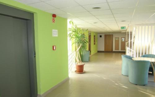 a hallway of an office with green walls and blue chairs at Szuperapartman in Zalakaros