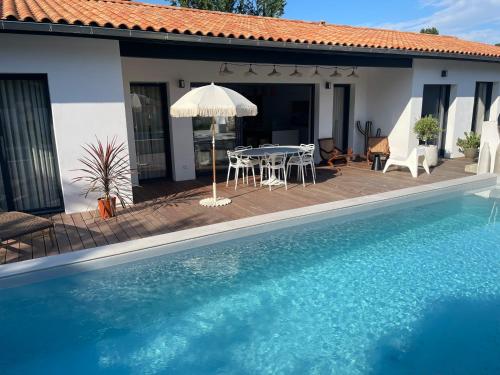 une maison avec une piscine et une table avec un parasol dans l'établissement Villa Elucci, à Arcangues