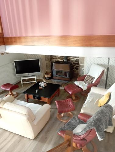 a living room with white furniture and a flat screen tv at Gite 12 personnes avec piscine in Malguénac