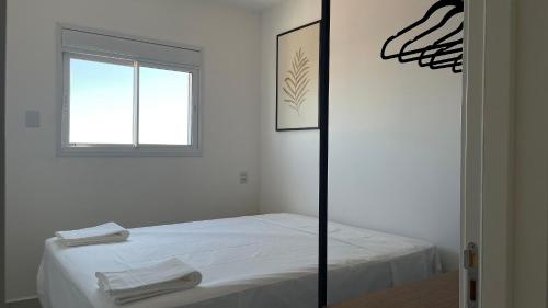a white room with a bed and a window at Apto com sacada gourmet e piscina – perto do centro de Bauru in Bauru