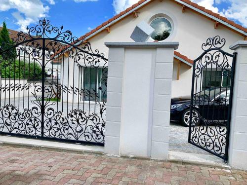 a white house with a black gate with a driveway at Studio proximité Paris Le Bourget in Arnouville-lès-Gonesse