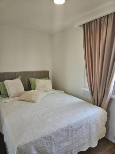 a bedroom with a bed with white sheets and a window at River Panorama Sarajevo in Sarajevo
