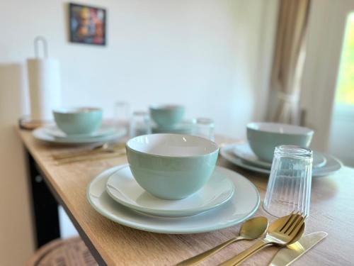 a wooden table topped with bowls and plates and spoons at Appartement idéal à 10 min de Disney pour 4 pers in Coupvray