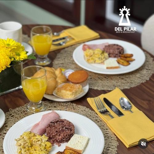 a table with plates of breakfast foods and glasses of orange juice at Del Pilar in Managua