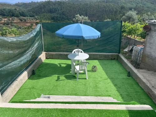 a table with an umbrella on top of grass at Encanto do Alva in Friumes