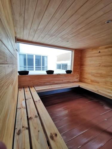 a wooden bench in a room with a window at Suites Cusco in Cusco