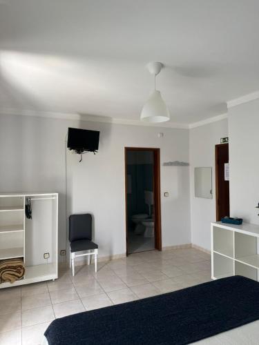 a living room with a television and a chair at Alojamento Dona Inês de Castro in Atouguia da Baleia