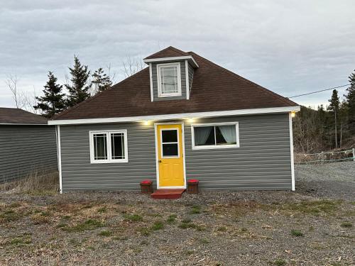 a small house with a yellow door in a yard at Hatchet Harbour Cottage in Herring Neck