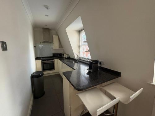 a small kitchen with a black counter top in a room at The Orderly By Estatesmen in London