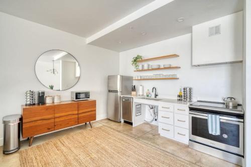 a kitchen with white cabinets and a sink and a mirror at Studio Bliss Dual-Queen Stay in Vibrant Alberta in Portland