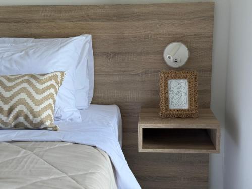 Una cama con reloj en una mesita de noche junto a ella en Sunrise Village Aptera Private Pool Villa, en Beritianá