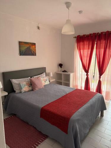 a bedroom with a large bed with red curtains at Alojamento Dona Inês de Castro in Atouguia da Baleia