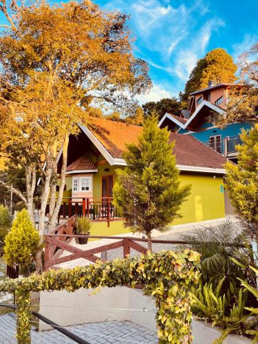 a yellow house with a wooden fence in front of it at Pousada Cantinho da Serra in Campos do Jordão