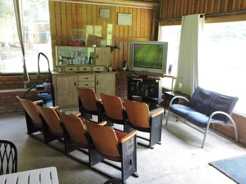 a living room with chairs and a tv and a tv at Pousada Sítio Paremi in Caxias do Sul