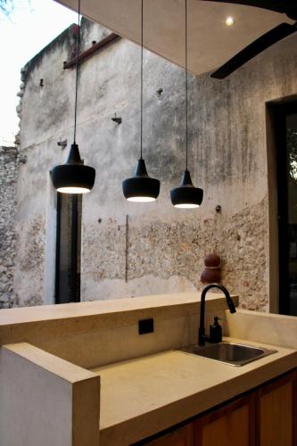 a kitchen with three pendant lights above a sink at CASA TAMA in La Ermita, Mérida Center with pool in Azcorra