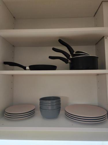 a shelf with plates and utensils in a kitchen at Stan na dan El Camino Pozarevac in Požarevac