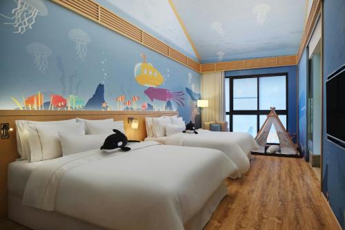 two beds in a hotel room with two cats sitting on them at The Westin Yilan Resort in Yuanshan