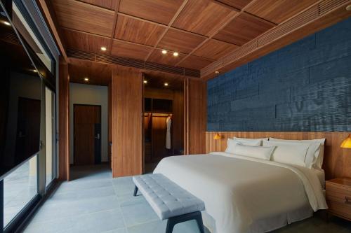 a bedroom with a large white bed and a bench at The Westin Yilan Resort in Yuanshan