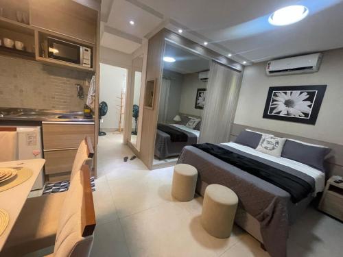a bedroom with a large bed and a kitchen at Flat Luxuoso a 500 m da Praia do Forte em Cabo Frio in Cabo Frio