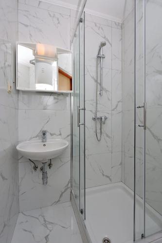 a white bathroom with a shower and a sink at Apartments with WiFi Lopar, Rab - 14804 in Lopar