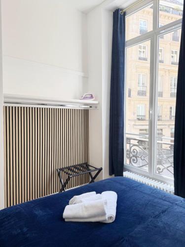 une chambre avec un lit bleu et une grande fenêtre dans l'établissement Richelieu Charm center of Paris, à Paris