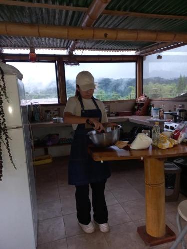 a woman in a kitchen preparing food in a bowl at Golden Bird in Mindo
