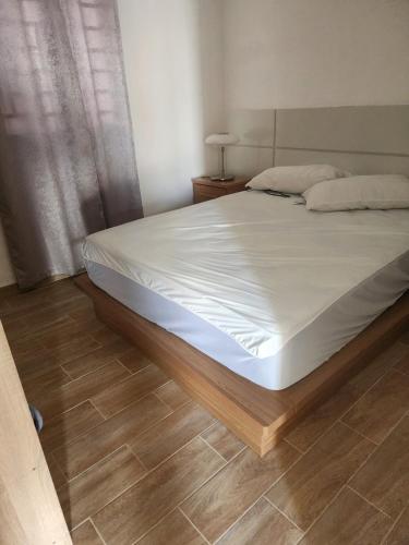 a bedroom with a bed with white sheets and a wooden floor at Residencias crasky in Punta Cana