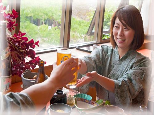 a woman sitting at a table drinking a glass of beer at Kirishima miyama hotel in Kirishima