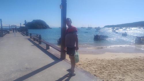 a person standing next to a window looking at the water at Pousada Ebenézer, Foguete in Cabo Frio