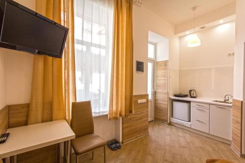W kuchni znajdują się żółte zasłony, biurko i okno. w obiekcie Mini Smart Apartments on Shpytalna 13- Economy Apartment w Lwowie
