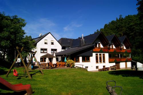 a large white house with a playground in the yard at Baunhöller-Mühle in Emmelshausen
