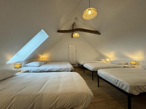 Cette chambre mansardée comprend 3 lits et une fenêtre. dans l'établissement Cottage in Saint-Vincent near Le Mans, à Saint-Vincent-du-Lorouër