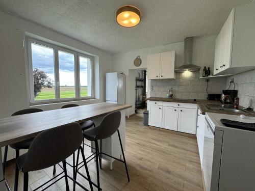 une cuisine avec des placards blancs et un comptoir avec des tabourets de bar dans l'établissement Cottage in Saint-Vincent near Le Mans, à Saint-Vincent-du-Lorouër