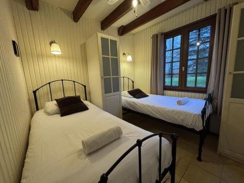 two beds in a room with two windows at Chalet in Aubigné-Racan with Pool & Garden in Aubigné-Racan